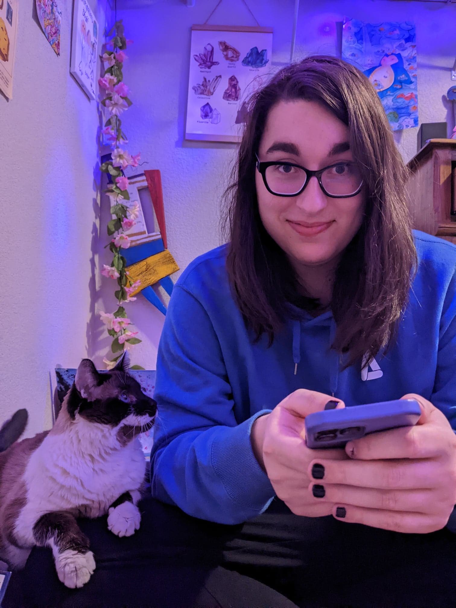 Ali in blue light with her white cat, Lily.